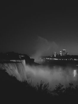 vue en contre-plongée sur les chutes du Niagara côté canadien avec un photographe au premier plan tenant un appareil photo, brume s'élevant de la cascade sous une lumière de fin de journée